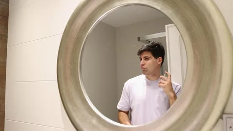 4k video man putting on cologne reflected in the mirror Stock Footage 262110147