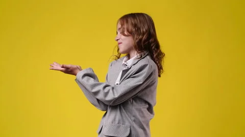 4k video of one girl pointing at left over yellow background. Stock Footage 234332853