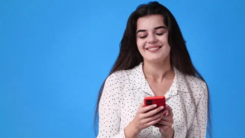 4k video of one girl using her phone over blue background. Stock Footage 228888133