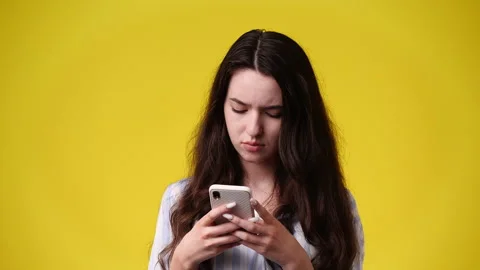 4k video of one girl using her phone over yellow background. Video stock 228889496
