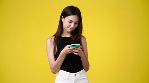 4k video of one girl using her phone over yellow background. Stock Footage 236419229