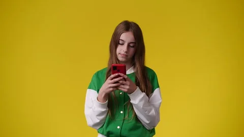 4k video of one girl using her phone over yellow background. Stock Footage 242612233