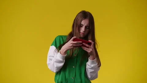 4k video of one girl using her phone over yellow background. Stock Footage 244464300