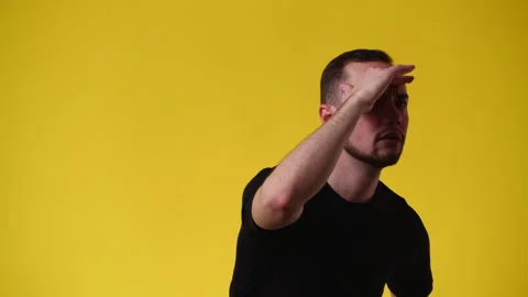 4k video of one man looking for someone and saying hello over yellow background. Stock Footage 240363045