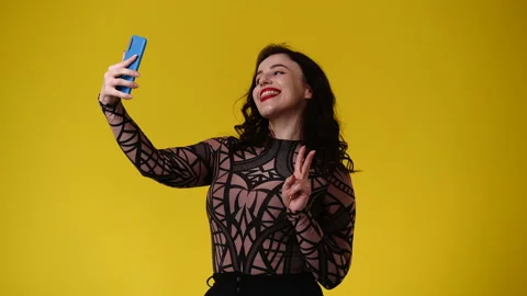 4k video of one woman using her phone over yellow background. Video stock 239643187