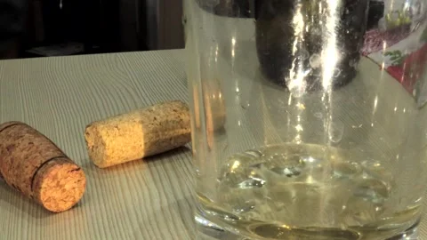 4k video, pour white wine into a transparent glass on the table near the cork Stock Footage 253706706