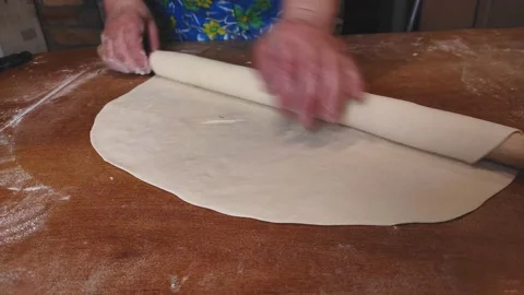 4K video. Rolling dough with a large rolling pin on the table female age hands Stock Footage 153895120
