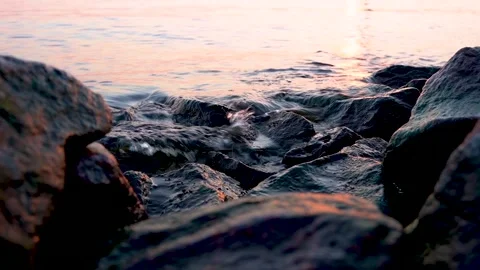 4k video. The sea waves beat the rocks near the shore at sunset Stock Footage 155979784