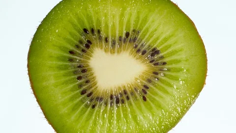 4k video of slice of kiwi fruit squeezing and exploding on white background Stock Footage