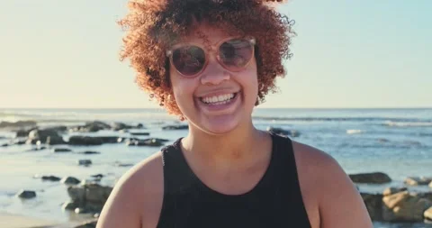 4K Video of Smiling Curly-Haired Woman with Peace Sign at Coastal Rocks with Stock Footage 305474535
