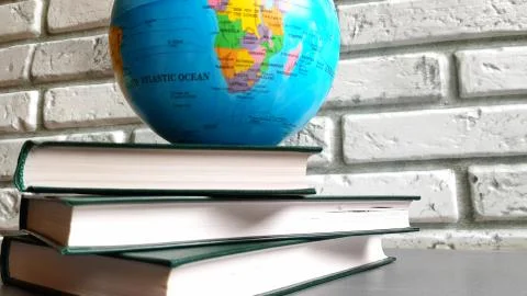 4K video a stack of books and a rotating globe against a gray brick wall, the Stock Photos