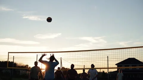 4k video Team playing beach valleyball on sunset. Youth having fun on beach at Stock Footage 212171979