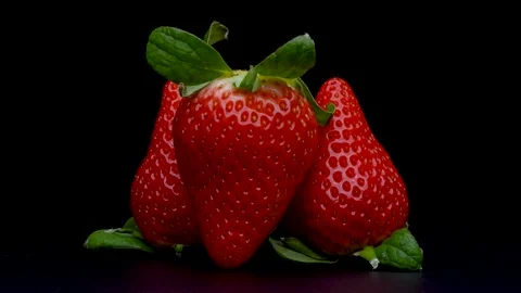 4K video of three turned strawberries on black background. Stock Footage 288565712