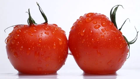 4K video of two tomatoes slowly turning on white background. Stock Footage 270121994