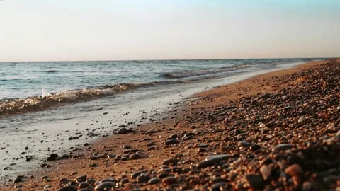4k video. Waves on the beach with pebbles at sunset, the sun goes into the water Stock Footage 161806107