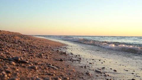 4k video. Waves on the beach with pebbles at sunset, the sun goes into the water Stock Footage 161806189