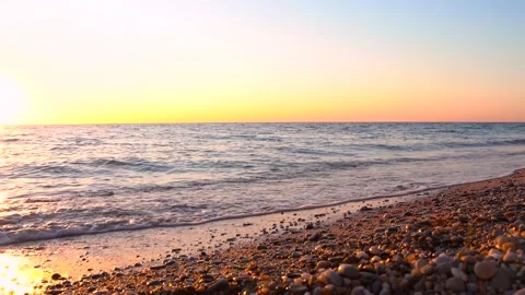 4k video. Waves on the beach with pebbles at sunset, the sun goes into the water Stock Footage 161806232