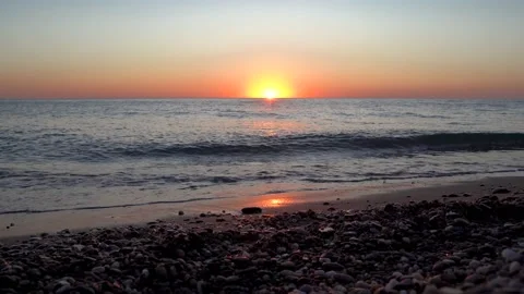 4k video. Waves on the beach with pebbles at sunset, the sun goes into the water Stock Footage 161806249