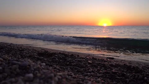 4k video. Waves on the beach with pebbles at sunset, the sun goes into the water Stock Footage 161806269