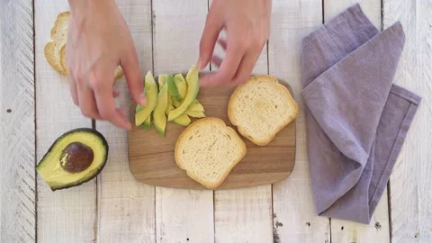4K video of a woman's hands putting avocado on a slice of bread. Concept of h Stock Footage 131849044