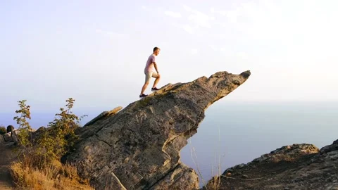 4k video. A young man climbs a steep cliff on a picturesque rocky ledge Stock Footage 160758495