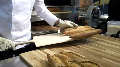 4K view of baker pulls out freshly baked baguettes from the oven. Stock Footage 104010327