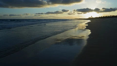 4K view of a beautiful sunrise with a cloudy blue skys as the waves break onto Stock Footage 102768875