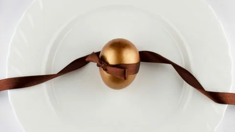 4K view of a golden Easter egg on a plate with a fork and knife Stock Footage 233454412