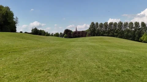 4K View of Green Meadow Surrounded by Trees Under Blue Sky Видео 337845502
