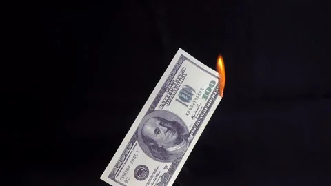 4K view of a hand with a match setting a dollar bill on fire. Stock Footage 253112459