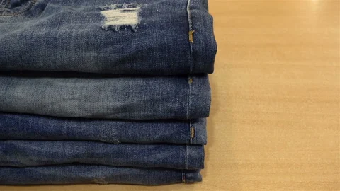 4K view of a hand taking jeans from a folded pile of jeans. Stock Footage 120512738
