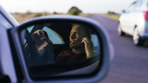 4K View in mirror of frustrated man talking in his car by the roadside Stock Footage 64968603