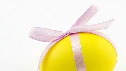4K view of painted yellow Easter egg with pink bow Stock Footage 236090607