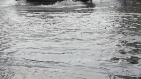 4K view of a puddle on the road and a passing car. Stock Footage 231411192