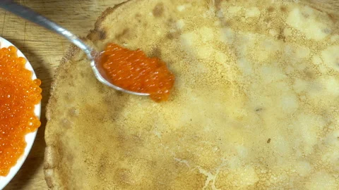4K view of red caviar is spooned and a pancake is wrapped Video stock 133396442