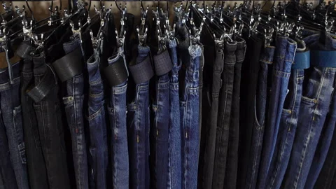 4k view of a row of jeans hanging on hangers on a rack. Stock Footage 114294918
