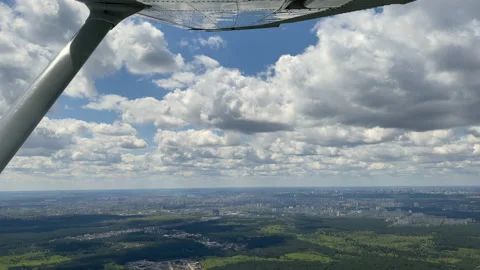 4K View from small airplane flying in clouds over forest and city Stock Footage 154373446