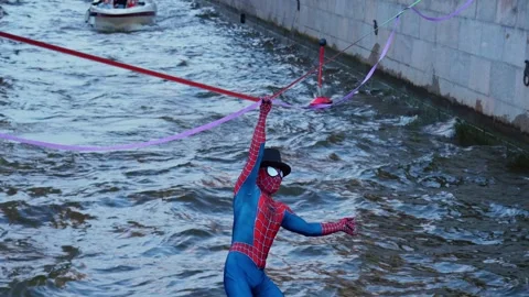 4k view of a street performer dressed as Spider-Man walking over river Stock Footage 343182568