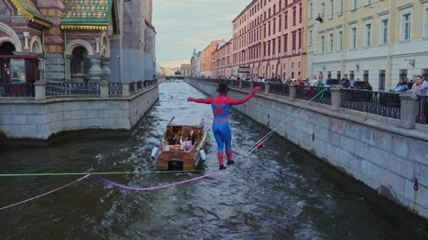 4k view of a street performer dressed as Spider-Man walking over river Stock Footage 343182615