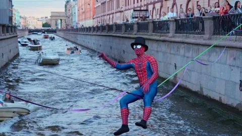 4k view of a street performer dressed as Spider-Man walking over river Stock Footage 343182634