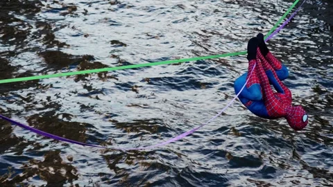 4k view of a street performer dressed as Spider-Man walking over river Stock Footage 343182695