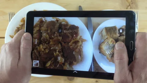 4K view on a tablet photographing plates with meat and fish Stock Footage 129290607