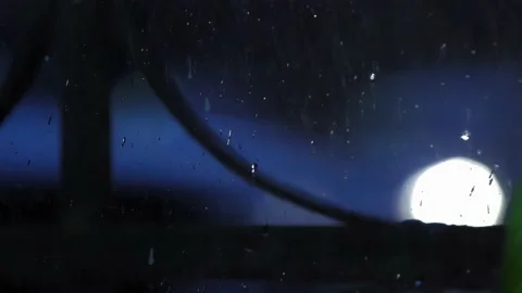 4K View through glass with raindrops, car headlights shine in bokeh Stock Footage 196487998