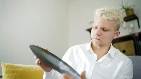 4K Vynil lover looking closely at new LP before putting it onto turntable Stock-Footage 136778082