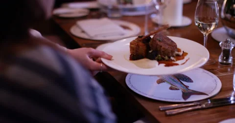 4K Waitress sets down dishes on the table in elegant gourmet restaurant Stock Footage