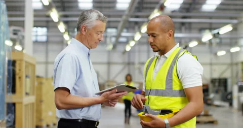 4k, Warehouse managers looking at tablet pc in a large warehouse. Slow motion. Stock Footage 68843473