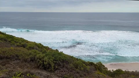 4k Waves crashing onto beach, hillside to the right 库存影片 277600834