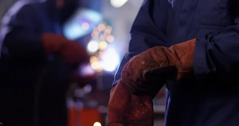 4K Welder in metalwork shop putting on gloves & safety visor, preparing to work Stock Footage