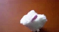 4K White wind-up fluffy toy bunny jumping across a brown wooden table 4k or 4k+ Resolution
