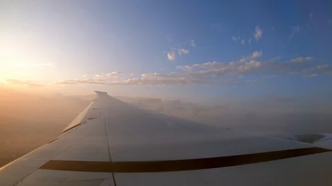 4K, Wing of plane and orange sunset as seen through an airplane window.-Dan Stock Footage 107775416